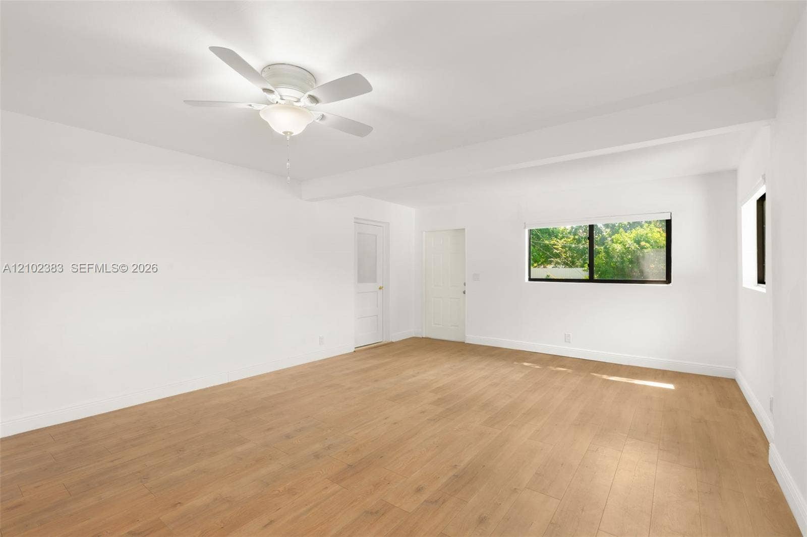 Family room featuring wood-finish flooring, white walls, a ceiling fan with integrated lighting, and multiple windows