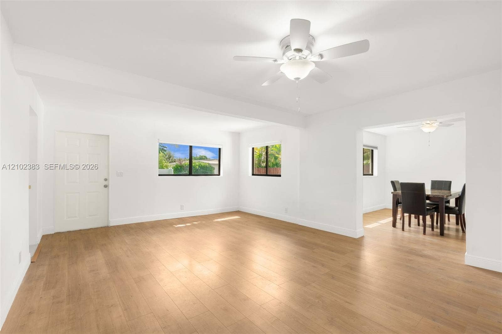 Family roomfeaturing wood-finish flooring, white walls, and a ceiling fan with integrated lighting