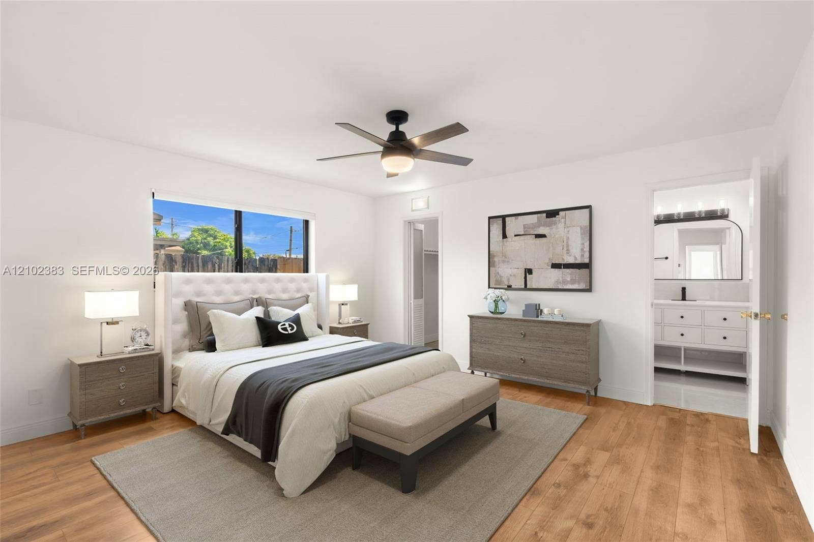 Primary bedroom featuring wood-finish flooring, a contemporary ceiling fan with integrated lighting, and a large window