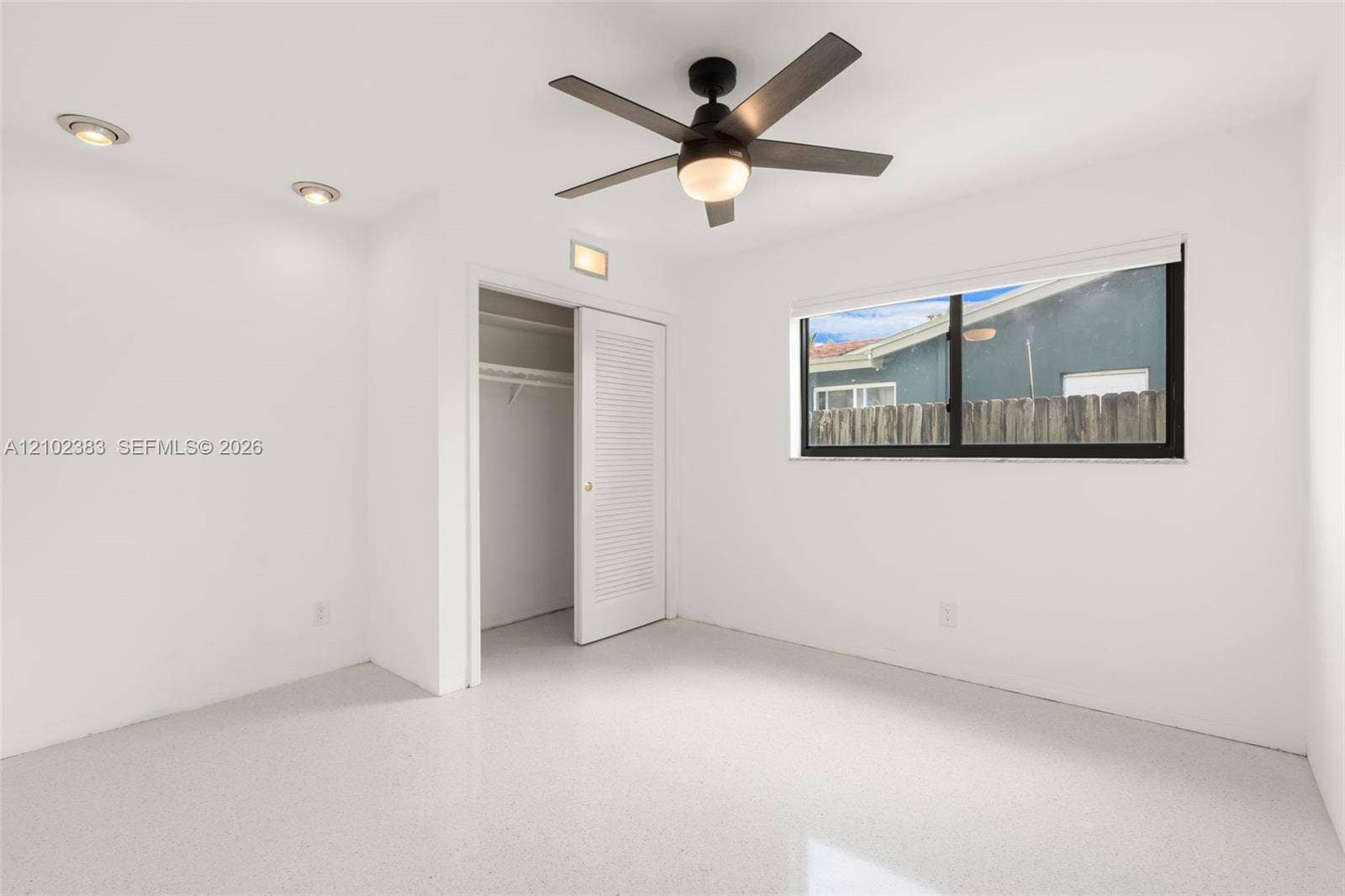 Bedroom 1 Neutral-toned terrazzo flooring, recessed lighting, ceiling fan with integrated light, and louvered closet door