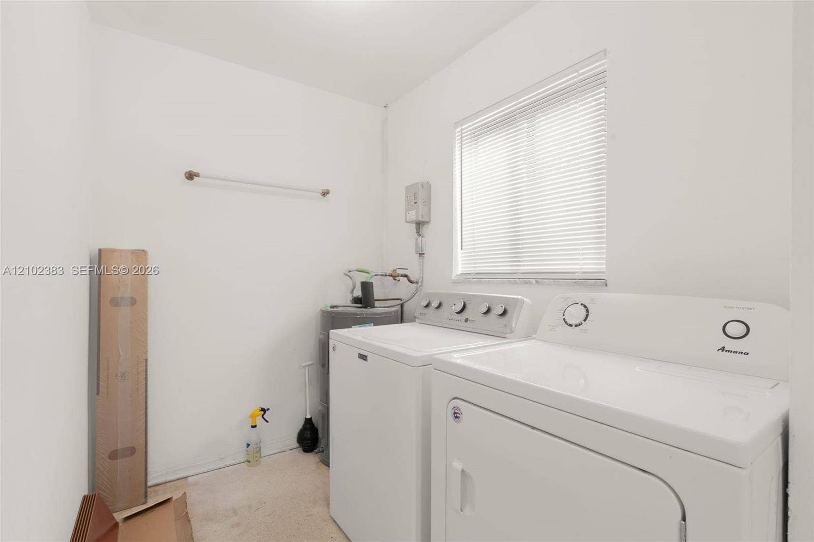 Laundry space featuring white walls, a horizontal window with adjustable blinds, and a built-in wall-mounted hanging rod