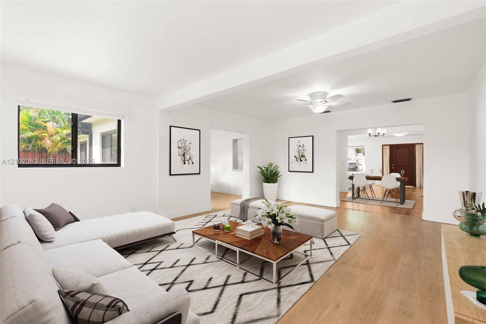 Open-concept interior featuring light wood-finish flooring, a neutral color palette, recessed ceiling lighting, and a multi-blade ceiling fan with an integrated light fixture