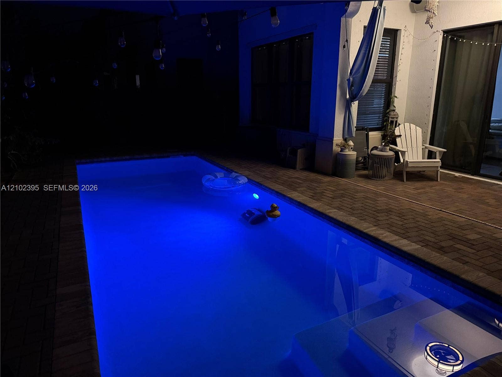 Rectangular in-ground pool with integrated lighting and brick-paver patio