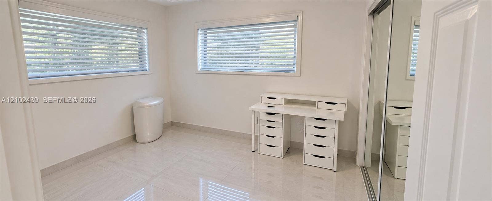 Tile flooring and two windows with blinds