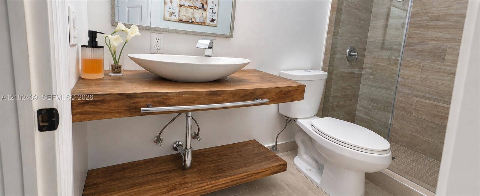 Floating wood vanity with integrated towel bar, vessel sink, and chrome faucet