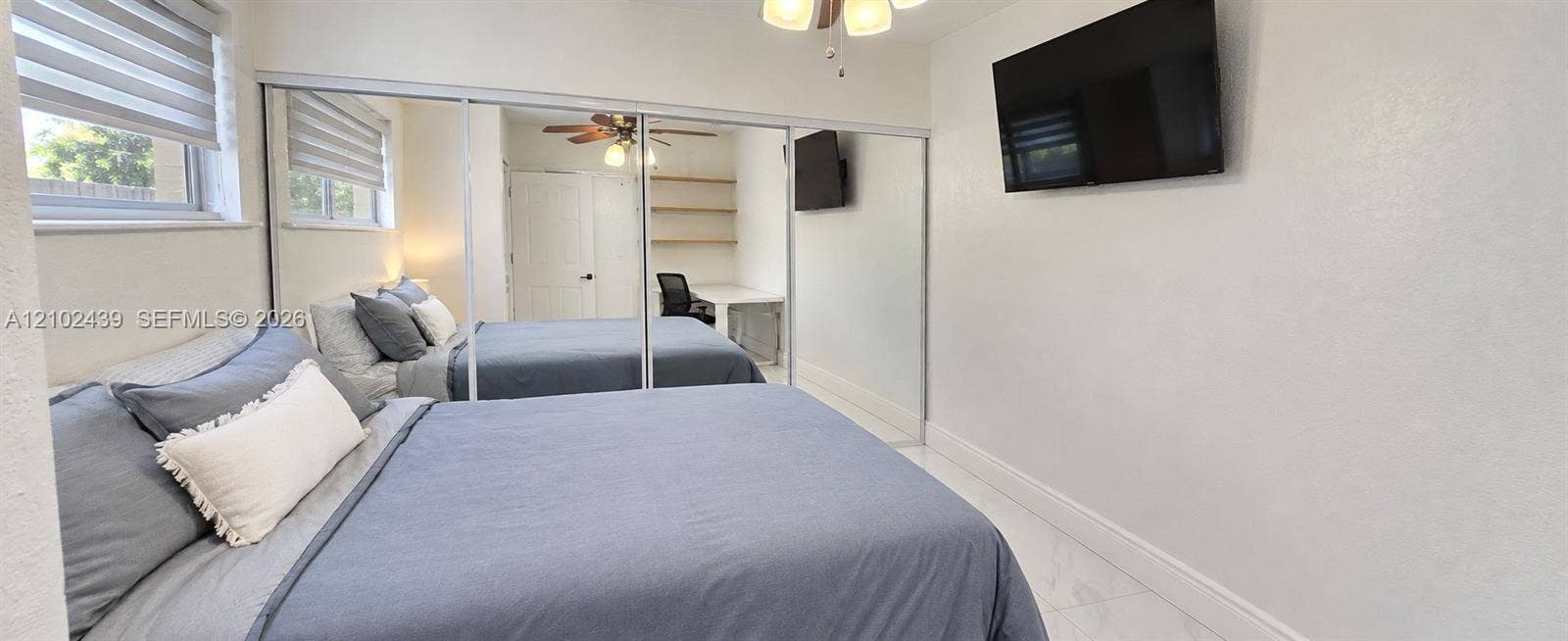 Recessed windows with horizontal blinds, full-length mirrored closet doors, and a ceiling fan with integrated lighting