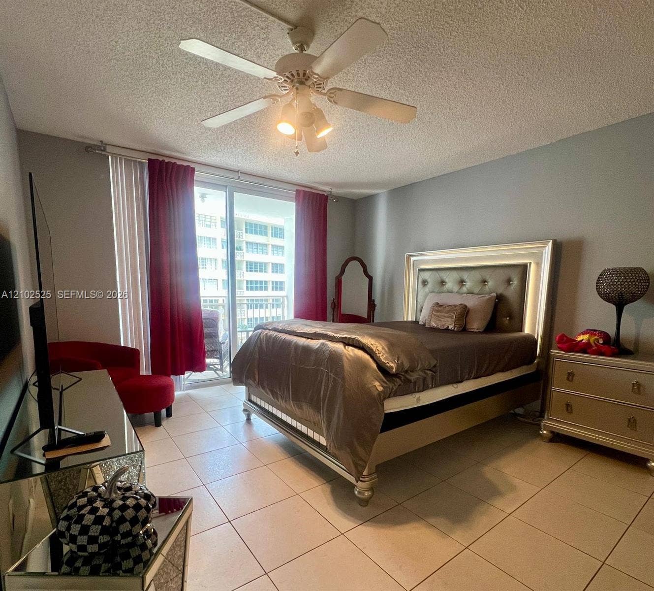 Neutral wall tones, ceramic tile flooring, ceiling fan with integrated lighting, and glass sliding doors providing exterior access