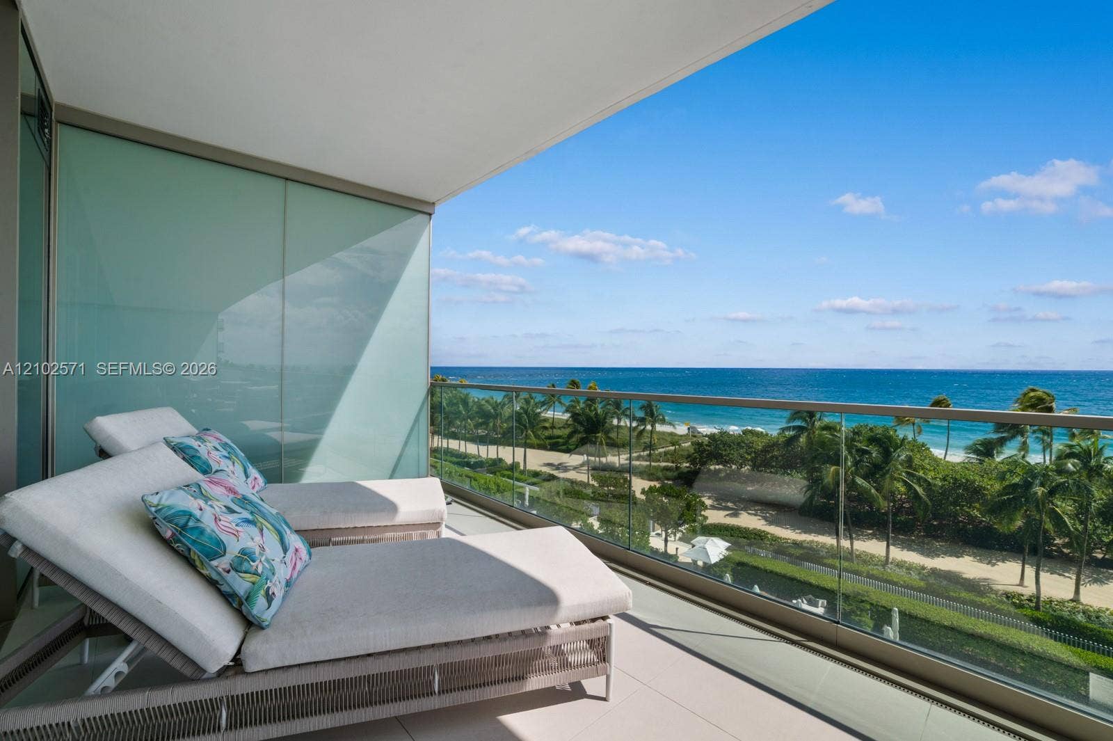 10201 Collins Avenue, #502, Bal Harbour, FL 33154 Covered terrace featuring large-format tile flooring, frosted glass privacy wall, and floor-to-ceiling glass panel railing with metal framing