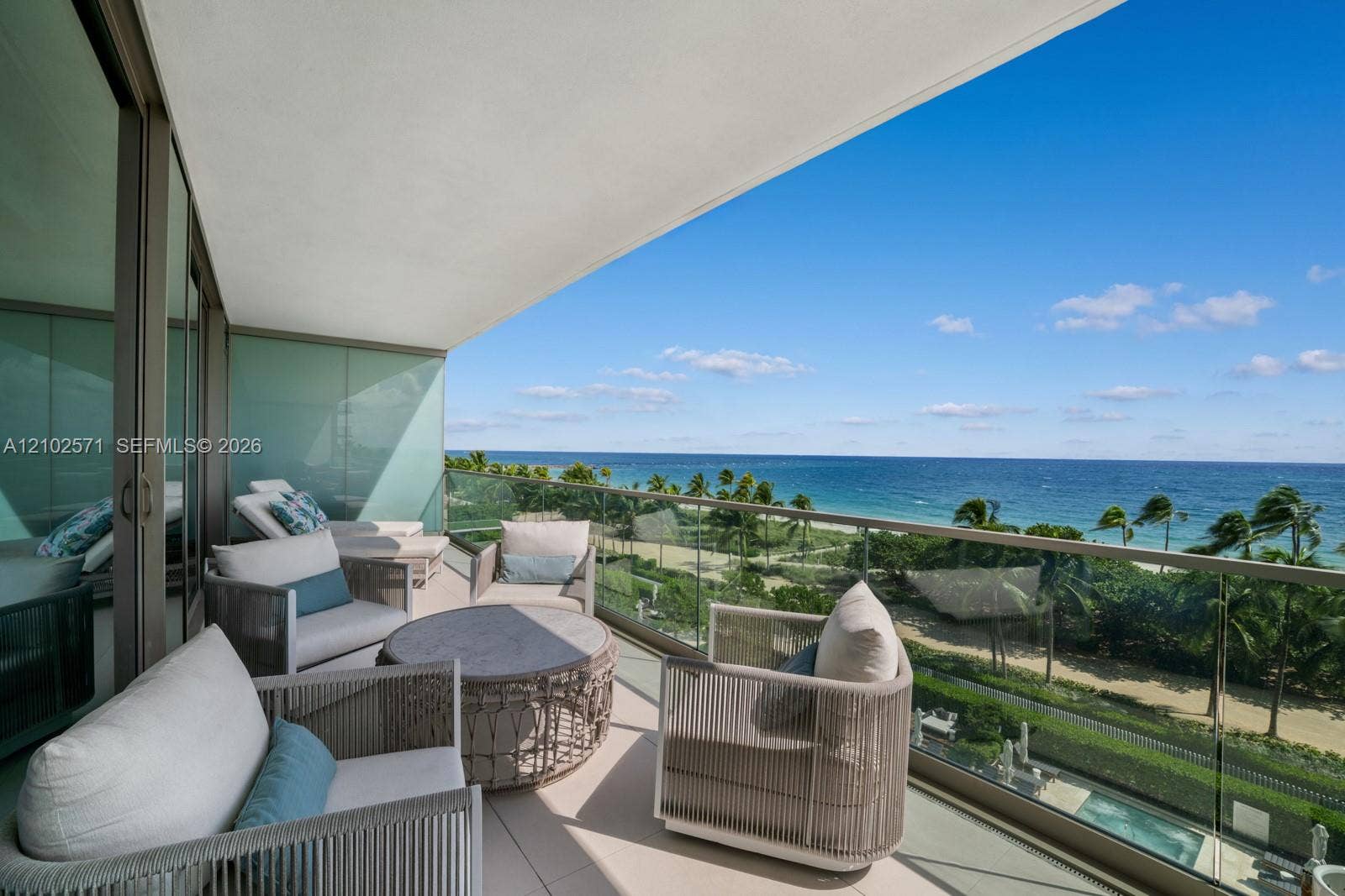 10201 Collins Avenue, #502, Bal Harbour, FL 33154 Covered balcony featuring a glass panel railing, tiled flooring, and floor-to-ceiling glass sliding doors
