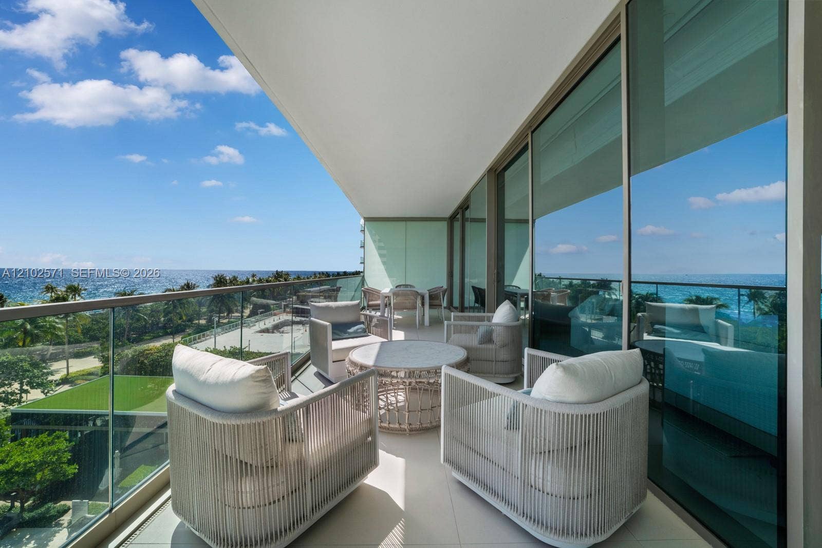 10201 Collins Avenue, #502, Bal Harbour, FL 33154 Covered balcony featuring oversized tile flooring, a glass panel railing, and full-height sliding glass doors