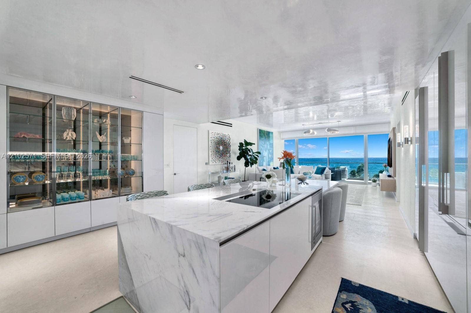10201 Collins Avenue, #502, Bal Harbour, FL 33154 Kitchen island featuring a stone waterfall countertop with an integrated cooktop and under-counter beverage refrigeration, floor-to-ceiling glass-front cabinetry, polished finish ceiling, recessed lighting, and floor-to-ceiling glass doors opening to an ocean backdrop
