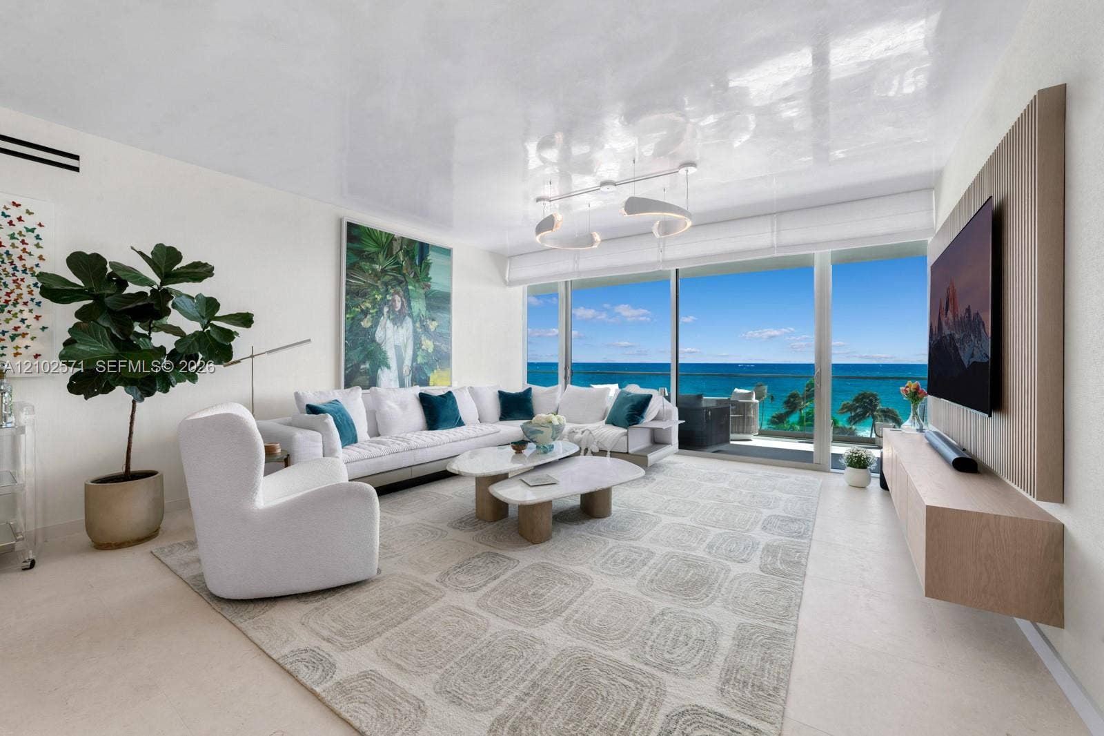10201 Collins Avenue, #502, Bal Harbour, FL 33154 Living area featuring floor-to-ceiling glass sliding doors, high-gloss ceiling finish, custom wall-mounted wood-finish media console, and direct ocean backdrop