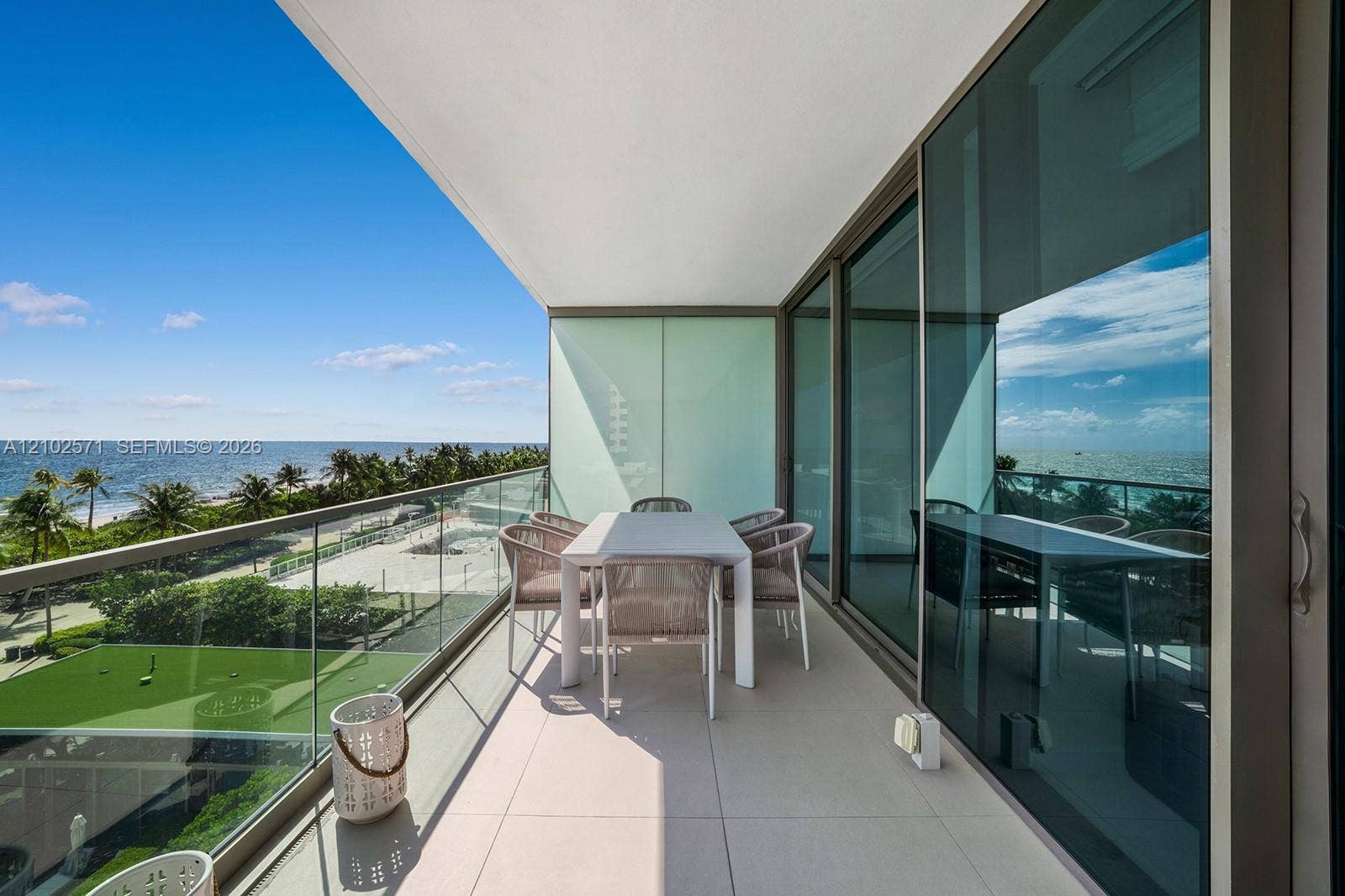 10201 Collins Avenue, #502, Bal Harbour, FL 33154 Covered balcony featuring expansive tile flooring, a glass-panel railing, and floor-to-ceiling sliding glass doors