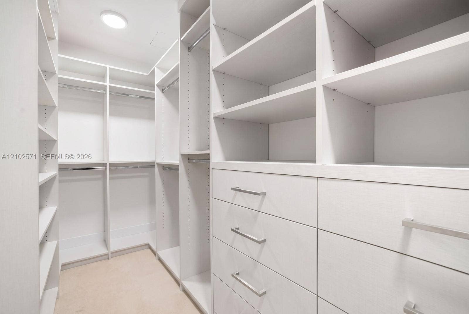 10201 Collins Avenue, #502, Bal Harbour, FL 33154 Walk-in closet featuring white custom cabinetry, adjustable shelving, integrated hanging rods, and built-in drawers with brushed nickel hardware