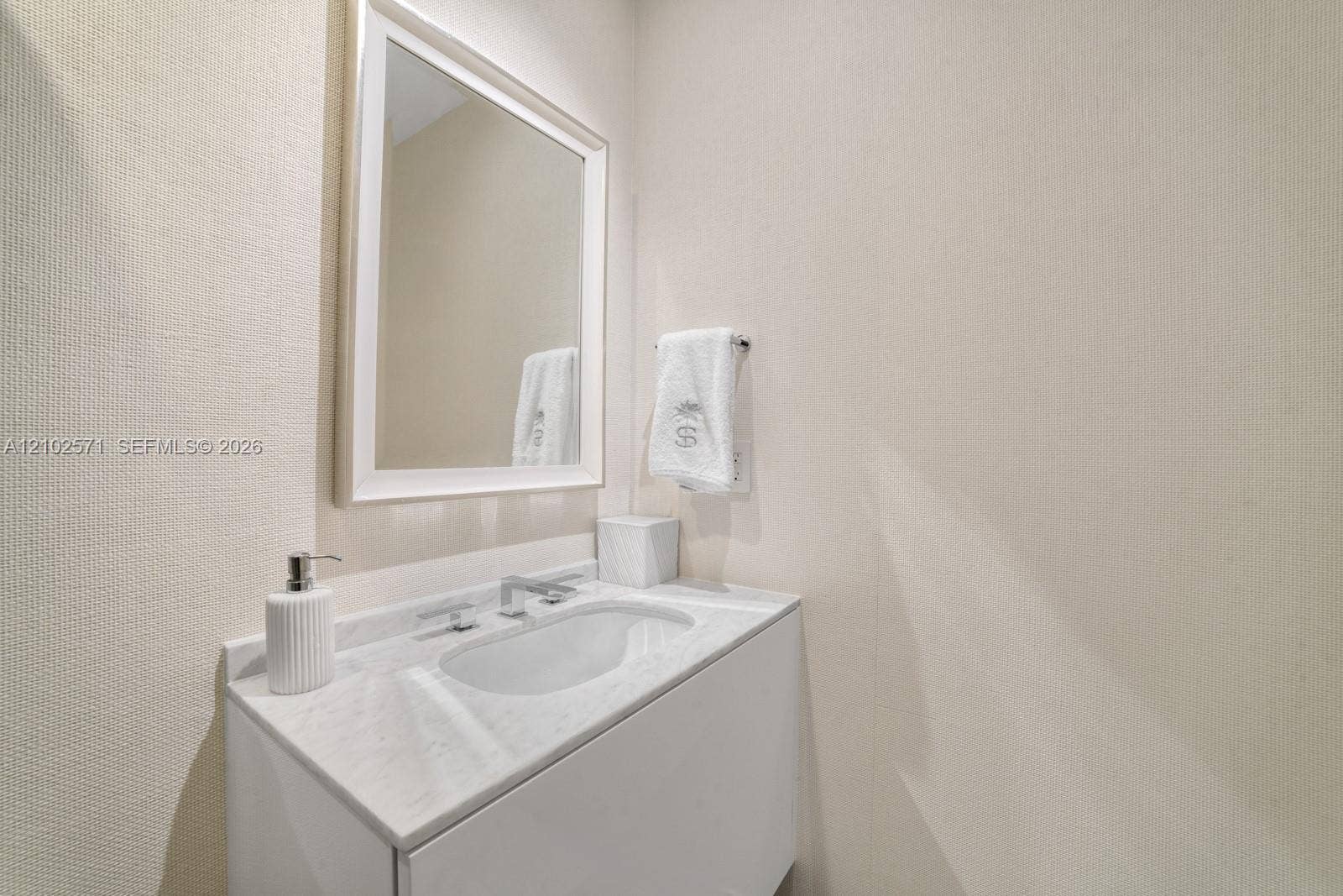 10201 Collins Avenue, #502, Bal Harbour, FL 33154 White vanity featuring a stone countertop with an integrated basin, a wall-mounted rectangular mirror, and a chrome single-lever faucet
