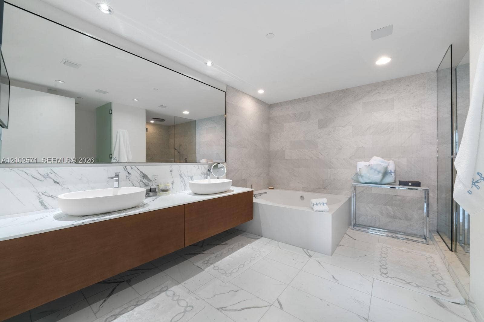 10201 Collins Avenue, #502, Bal Harbour, FL 33154 Floating wood-finish vanity with dual vessel sinks, expansive wall-mounted mirror, soaking tub, and tile flooring