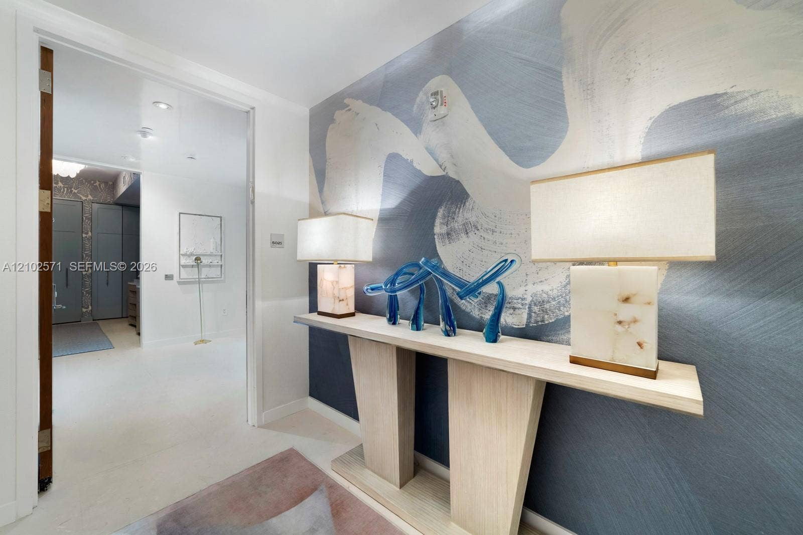 10201 Collins Avenue, #502, Bal Harbour, FL 33154 Wall-mounted console table with a minimalist aesthetic and integrated large-format feature wall mural