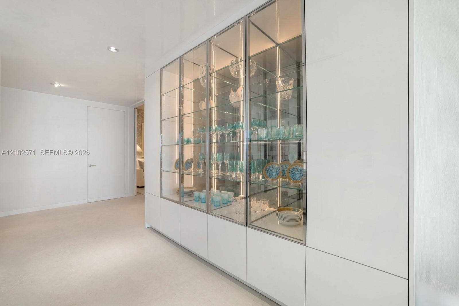 10201 Collins Avenue, #502, Bal Harbour, FL 33154 Built-in floor-to-ceiling cabinetry featuring white panel doors and glass-fronted display sections with integrated interior lighting