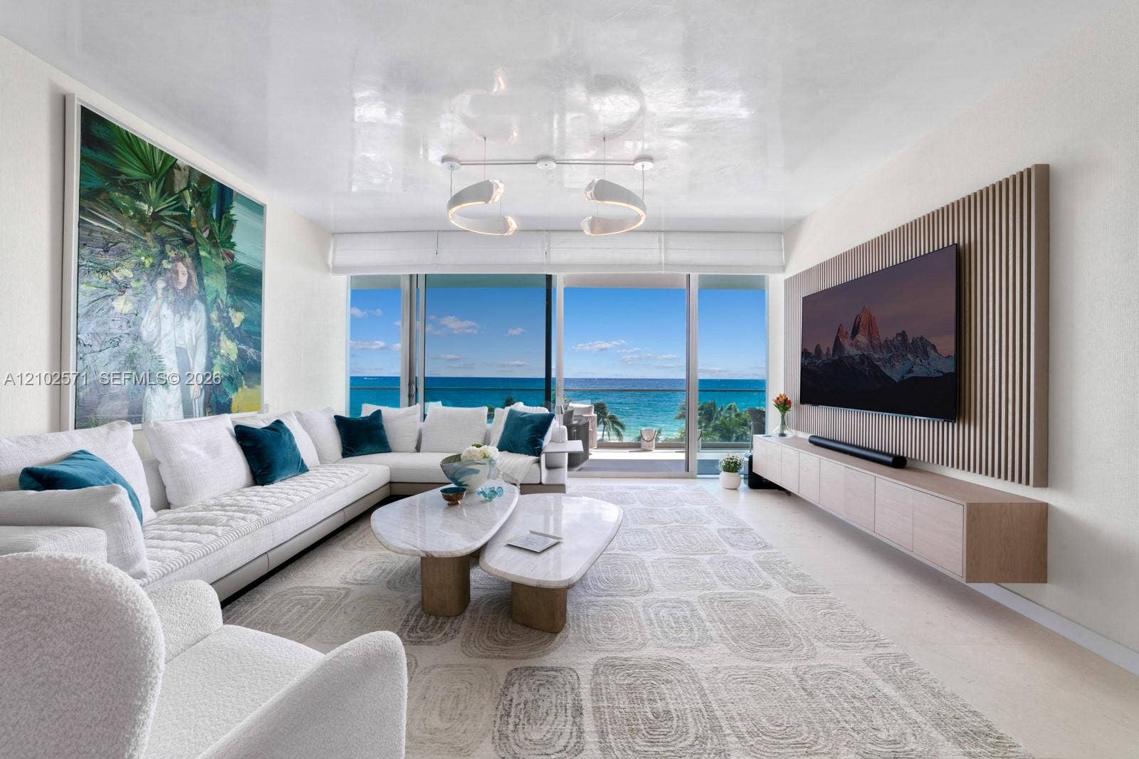 10201 Collins Avenue, #502, Bal Harbour, FL 33154 Floor-to-ceiling sliding glass doors, custom wood-slat wall paneling, wall-mounted floating cabinetry, modern curvilinear pendant lighting, and high-gloss ceiling finish