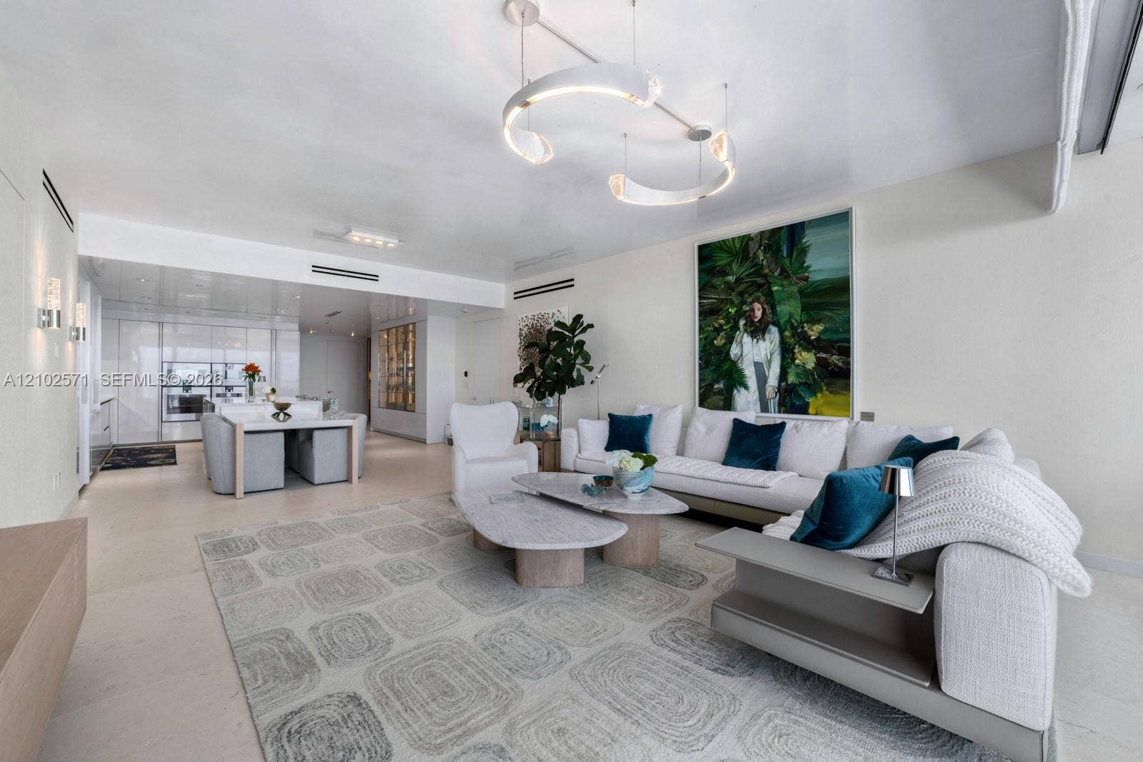 10201 Collins Avenue, #502, Bal Harbour, FL 33154 Open-concept main living area featuring stone-finish flooring, recessed linear lighting, a contemporary curved pendant chandelier, and sleek built-in cabinetry