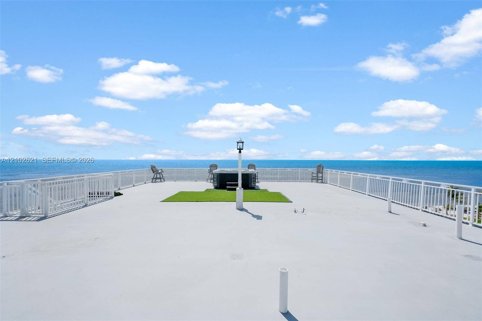 Expansive rooftop deck featuring a hot tub, artificial turf area, and perimeter white railings