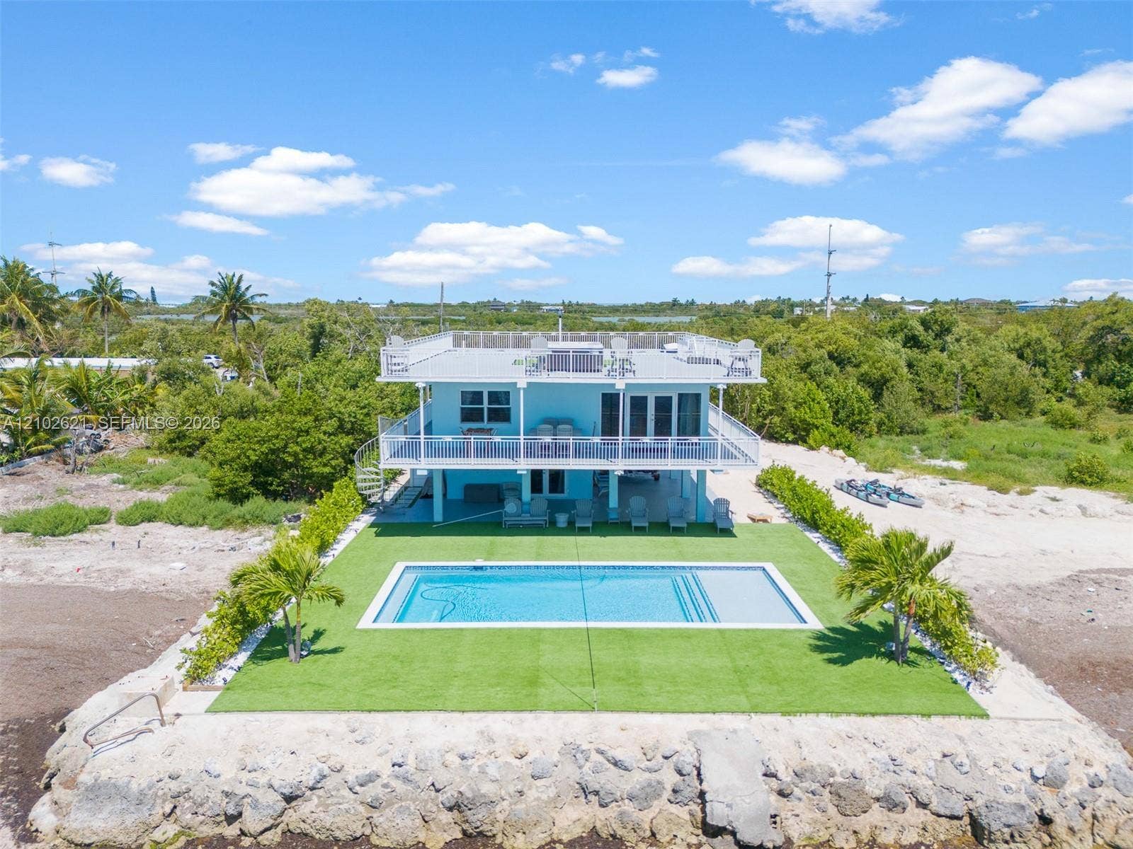 Elevated two-story residence featuring a rooftop deck, an inground swimming pool, a ground-level patio, a second-story balcony, and a spiral staircase