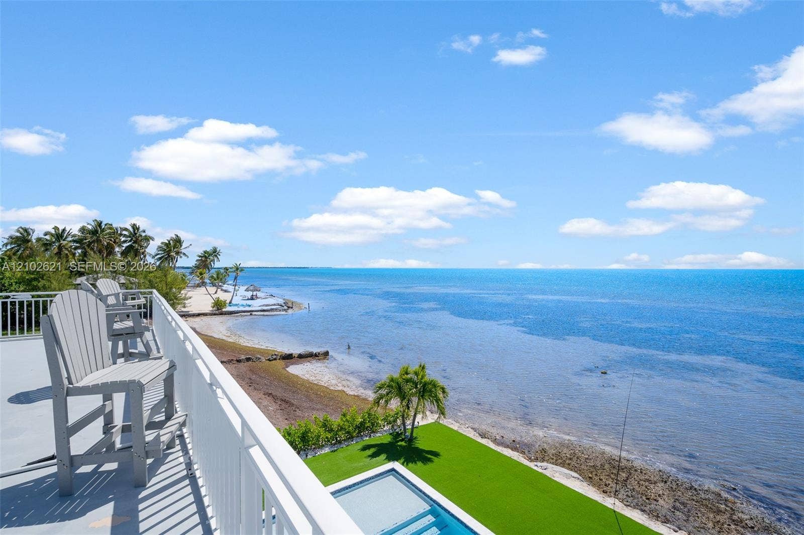 Waterfront property featuring a private pool, artificial turf landscaping, and a white railing balcony