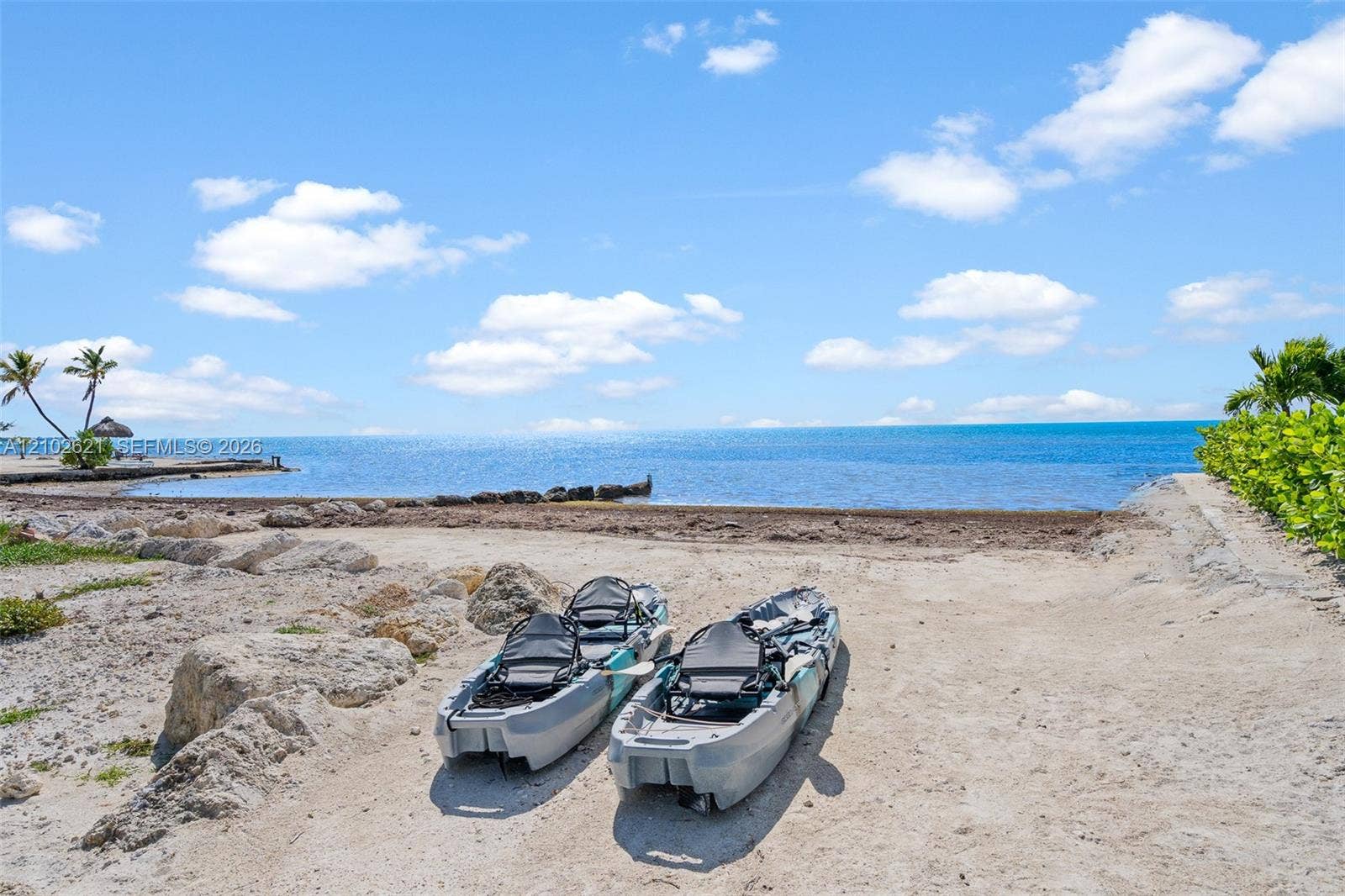 Sandy beach access, turquoise water, tropical foliage, and rock formations