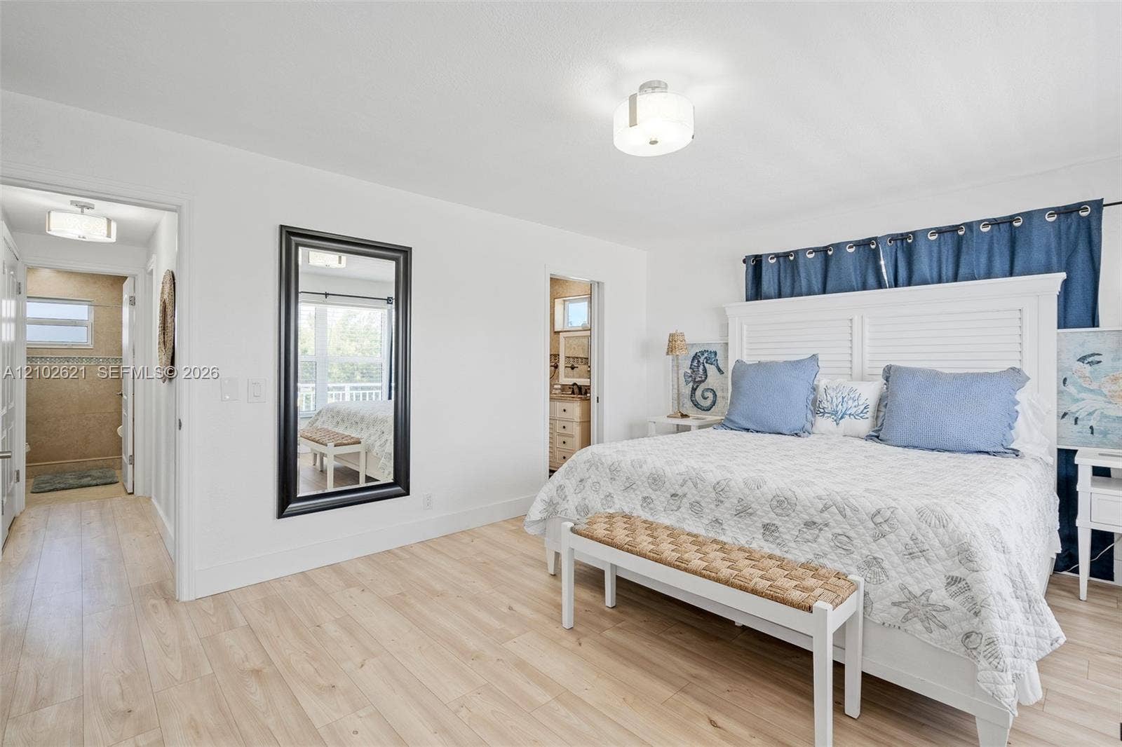 Wood-finish flooring, white walls, flush mount lighting, and an adjacent tiled bathroom