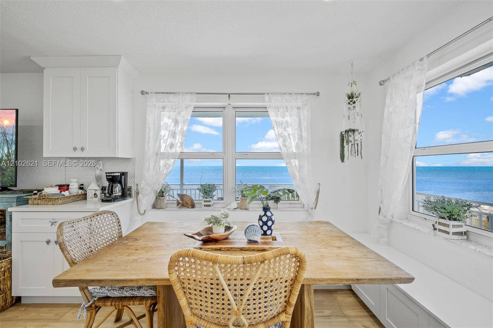 Built-in window bench seating with storage, white shaker-style cabinetry, and a white subway tile backsplash