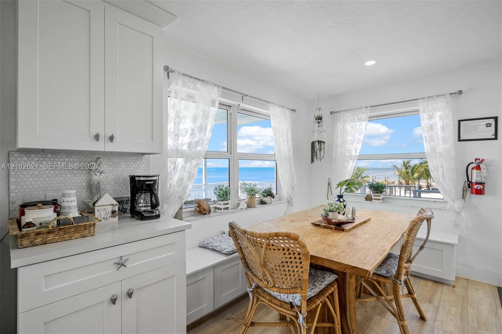 Built-in bench seating, wood-finish flooring, white shaker-style cabinetry, and hexagonal mosaic tile backsplash
