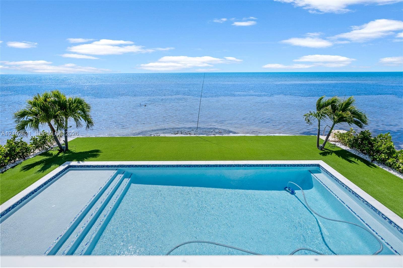 Waterfront setting with a rectangular pool featuring steps and an integrated sun shelf