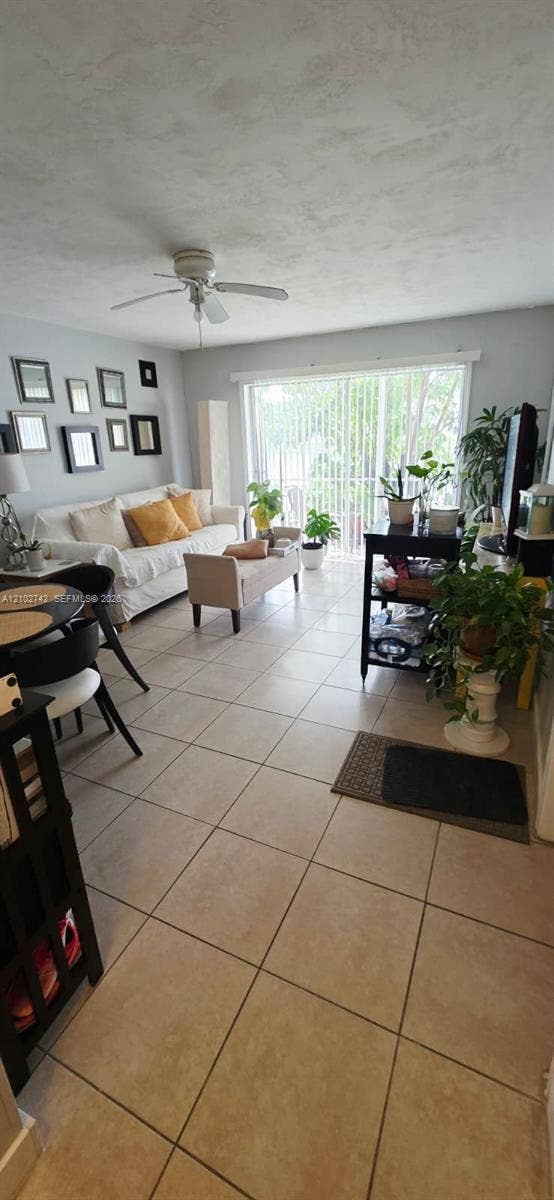 2800 NE 203rd Street, #8, Aventura, FL 33180 Neutral tile flooring, ceiling fan, and sliding glass door with vertical blinds