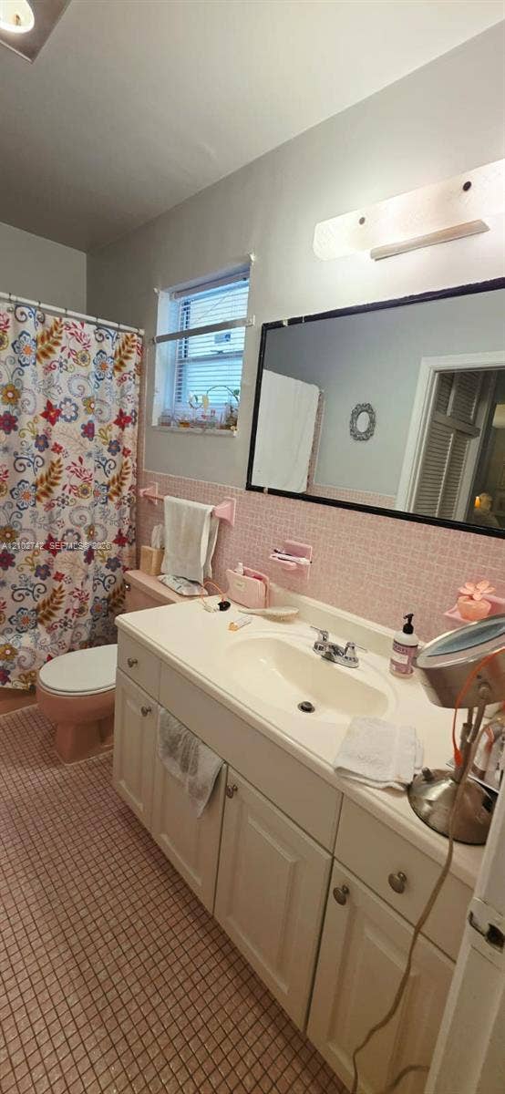2800 NE 203rd Street, #8, Aventura, FL 33180 Bathroom featuring white cabinetry, integrated sink, large wall-mounted mirror, mosaic-tiled walls, and a multi-light fixture