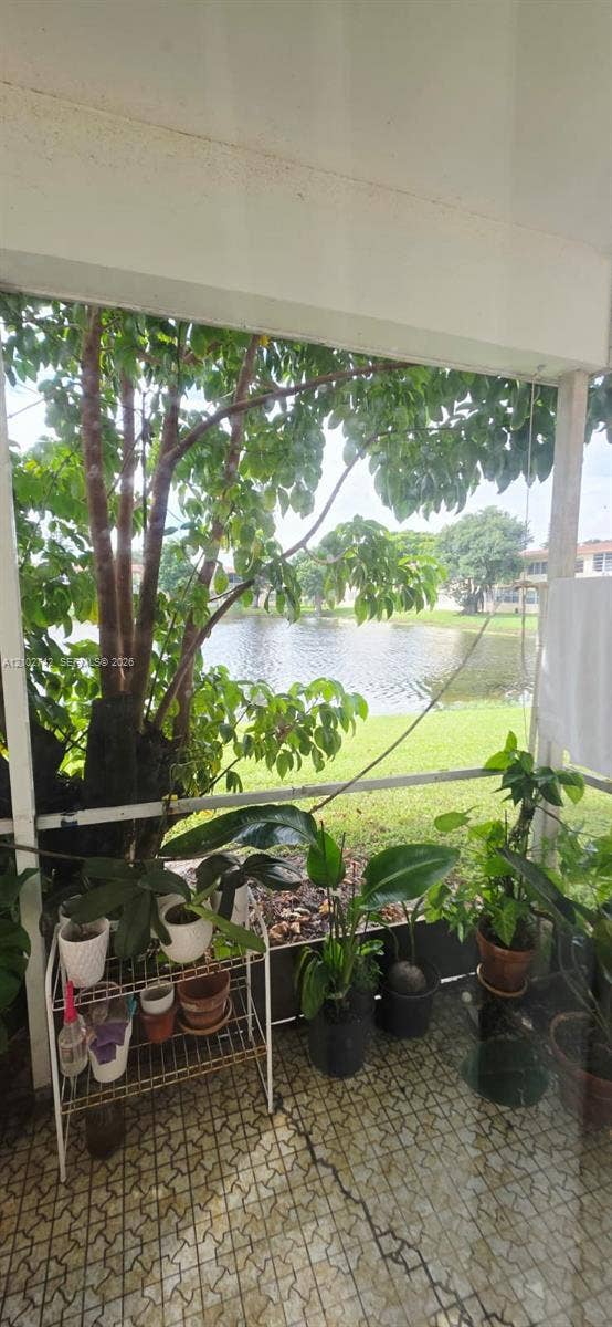 2800 NE 203rd Street, #8, Aventura, FL 33180 Screened lanai featuring tiled flooring, structural support pillars, and direct exterior access to a pond