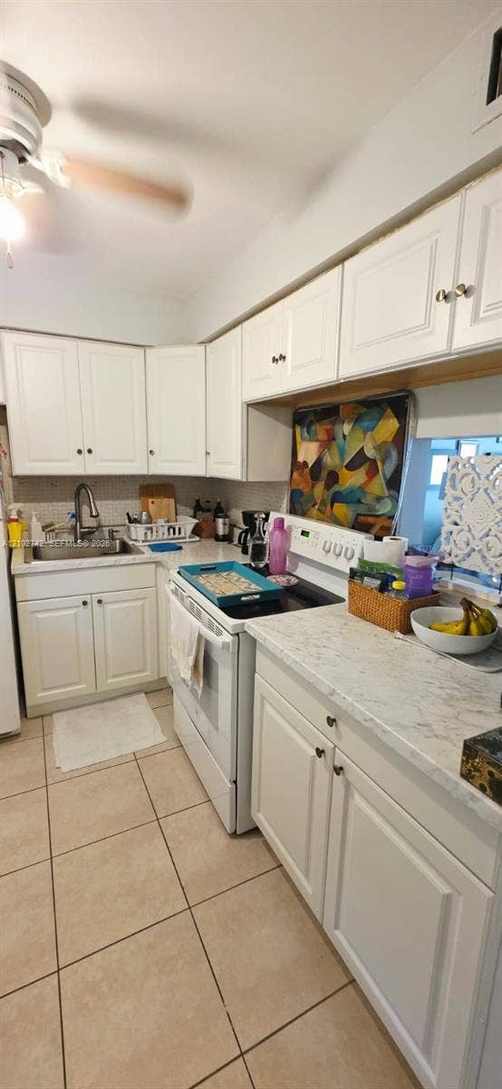 2800 NE 203rd Street, #8, Aventura, FL 33180 Kitchen featuring white shaker-style cabinetry, stone-patterned countertops, stainless steel sink with a high-arch faucet, integrated ceiling fan, and tile flooring