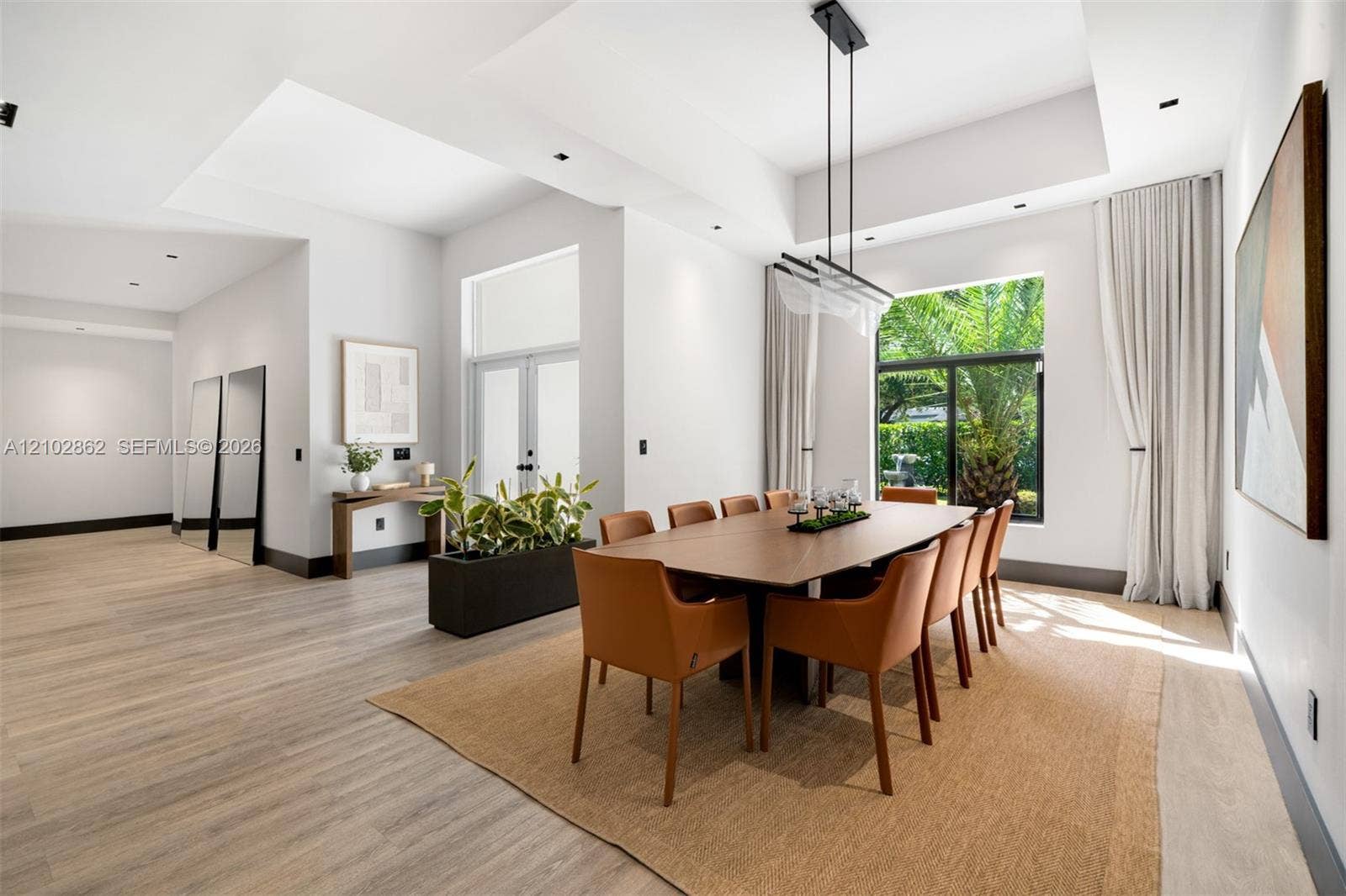 Tray ceilings with recessed lighting, wood-finish flooring, large-format windows, modern linear chandelier, and double-door entry