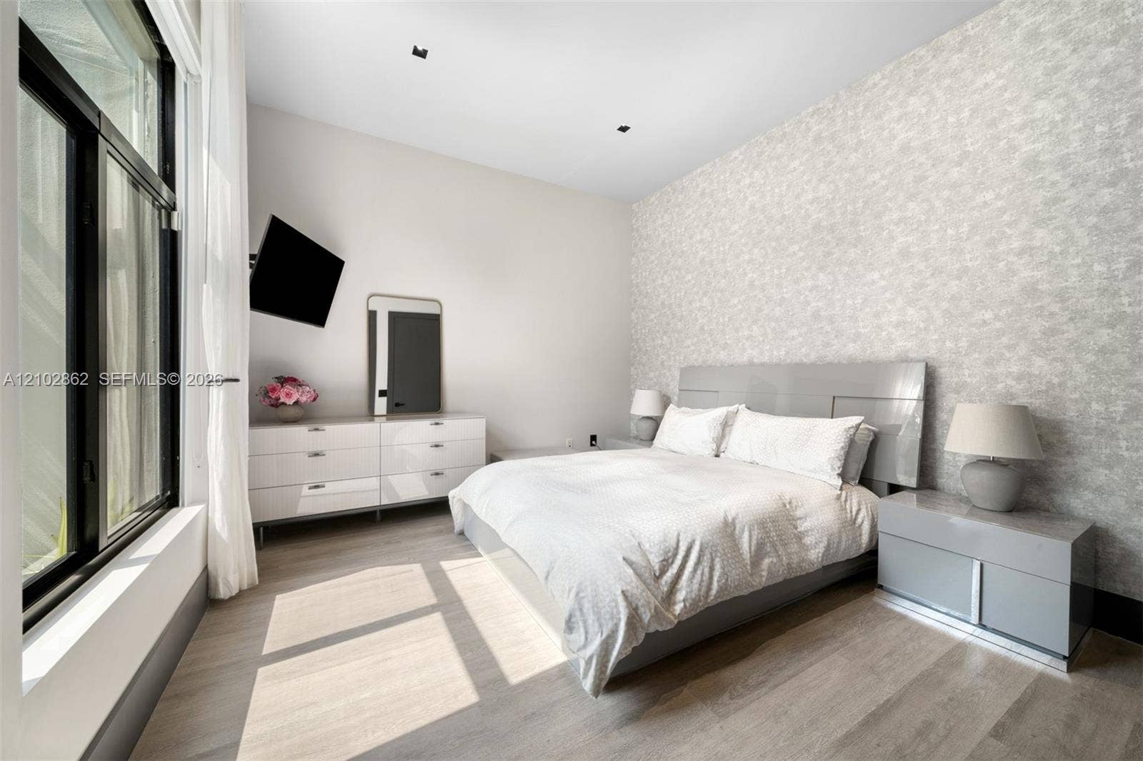 Bedroom featuring textured accent wall, floor-to-ceiling windows, recessed lighting, and wood-finish flooring