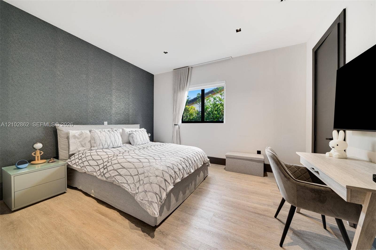 Textured charcoal accent wall featuring recessed ceiling lighting, light wood-finish flooring, and black window trim