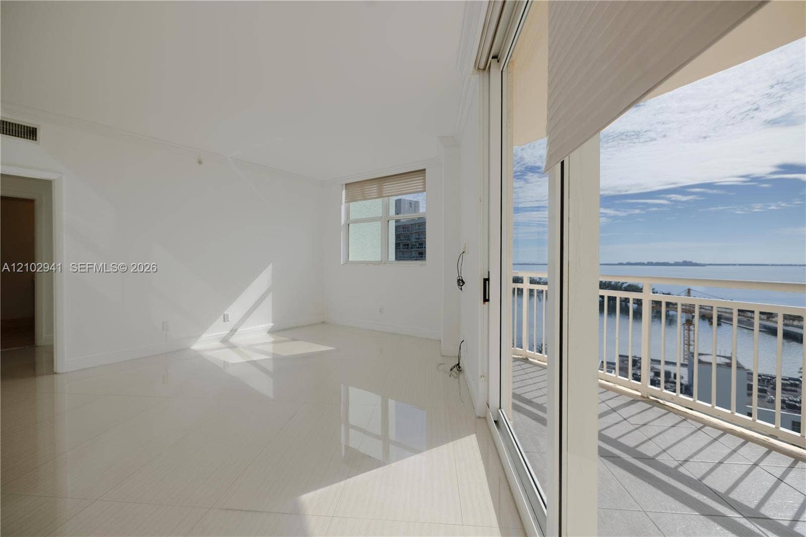 2475 Brickell Avenue, #1807, Miami, FL 33129 Interior space featuring polished tile flooring, full-height sliding glass doors, and a private balcony with metal railing