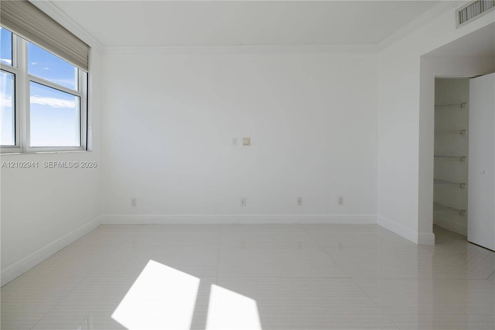 2475 Brickell Avenue, #1807, Miami, FL 33129 Neutral-toned large-format tile flooring, multi-pane window with retractable shade, and built-in closet with integrated shelving