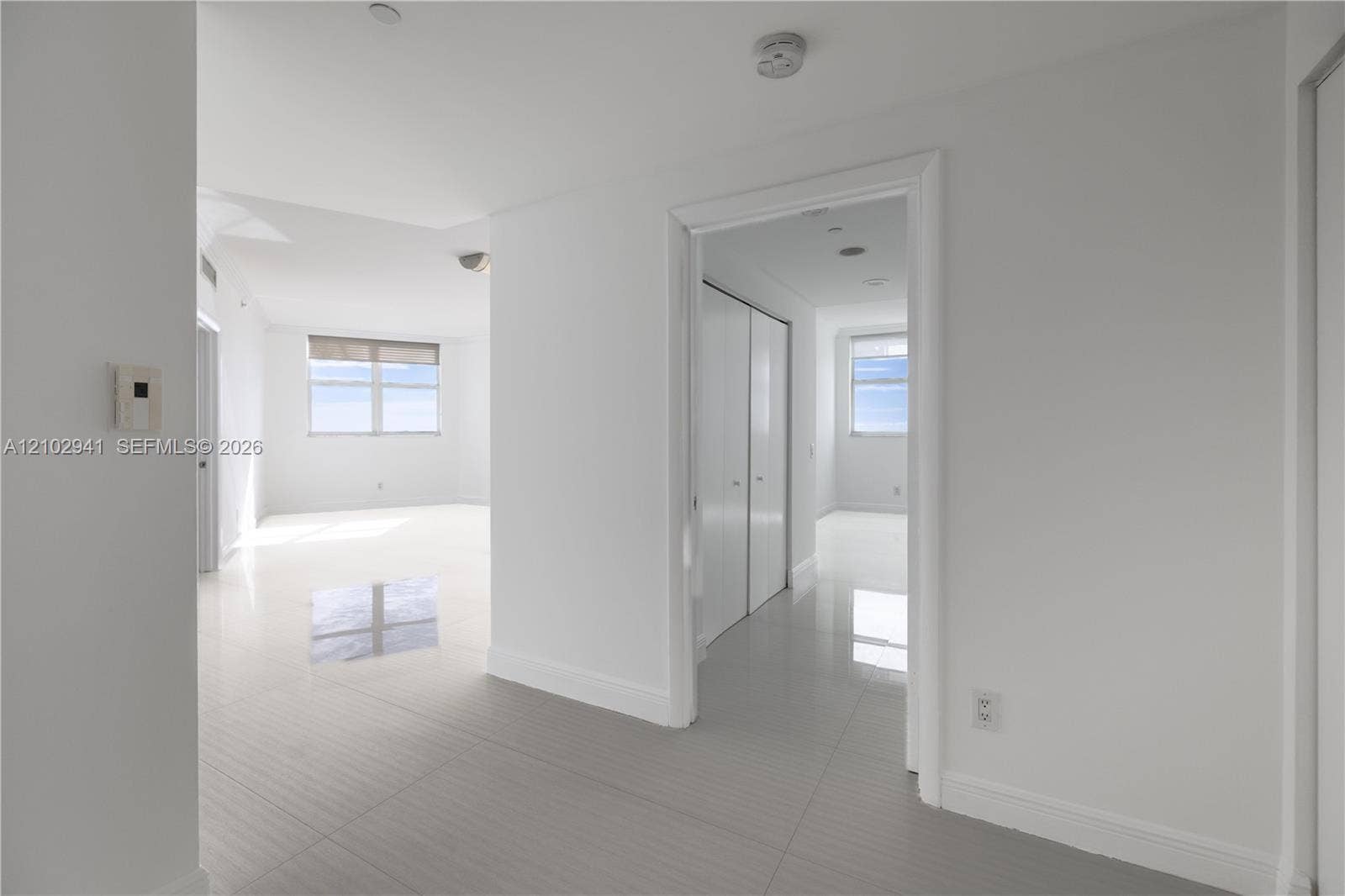 2475 Brickell Avenue, #1807, Miami, FL 33129 Interior space featuring polished tile flooring, white walls, and floor-to-ceiling closets with sliding panel doors