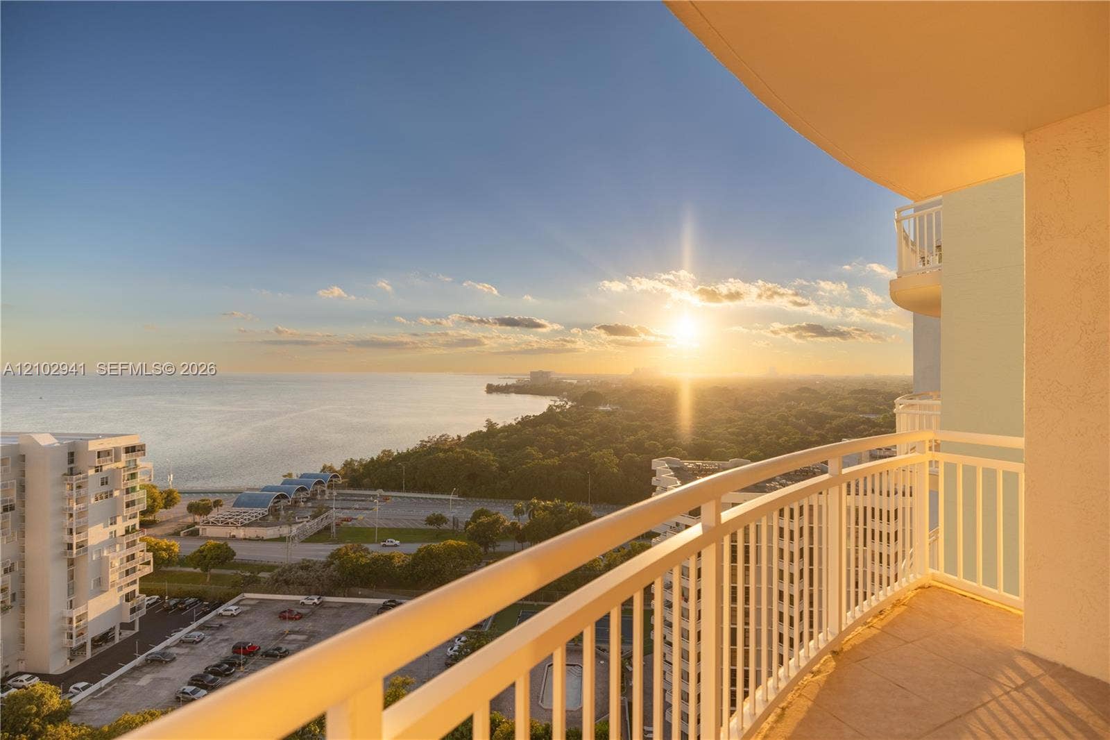 2475 Brickell Avenue, #1807, Miami, FL 33129 Covered outdoor balcony featuring white railings, tiled flooring, and sweeping panoramic ocean and coastal scenery