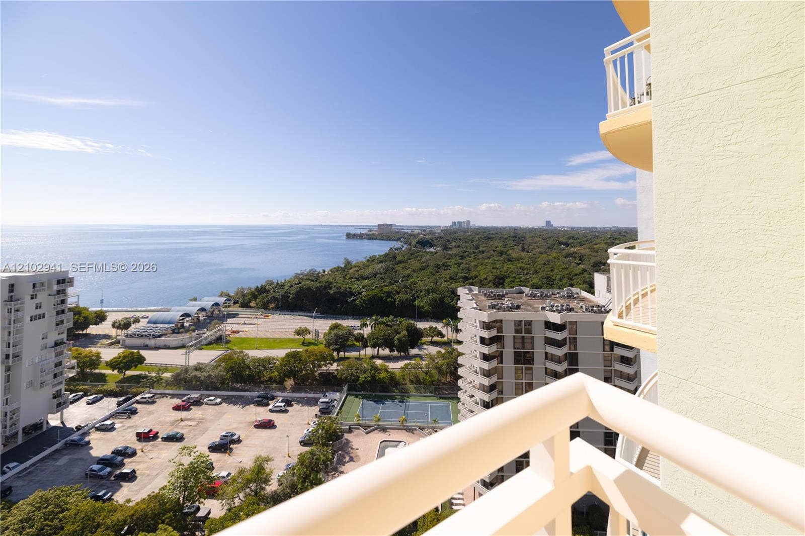 2475 Brickell Avenue, #1807, Miami, FL 33129 Private balcony with white metal railings featuring expansive coastal scenery and proximity to a community tennis court