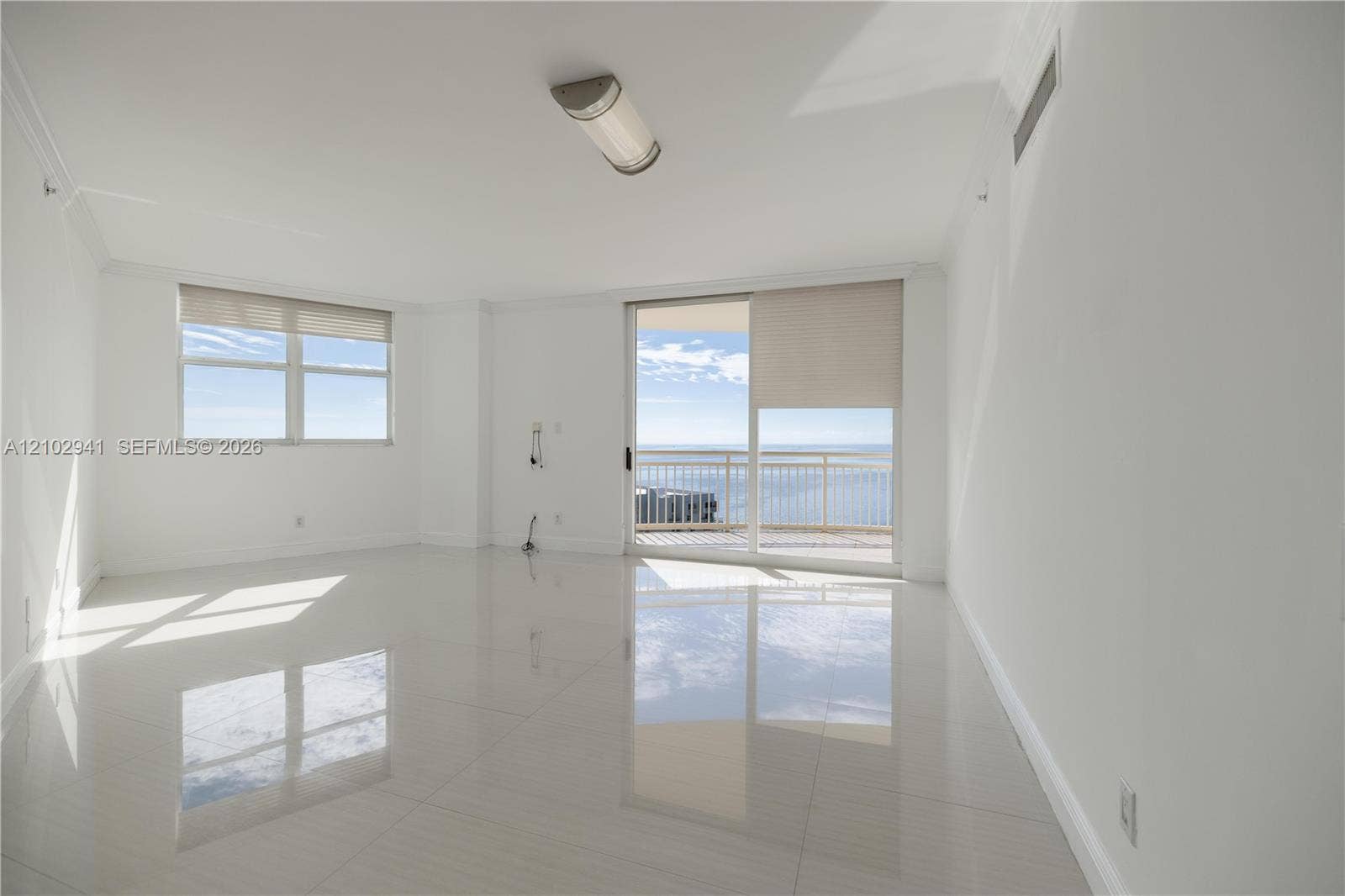 2475 Brickell Avenue, #1807, Miami, FL 33129 Bright living area featuring large-format polished tile flooring, sliding glass doors to a balcony, neutral wall tones, and expansive windows
