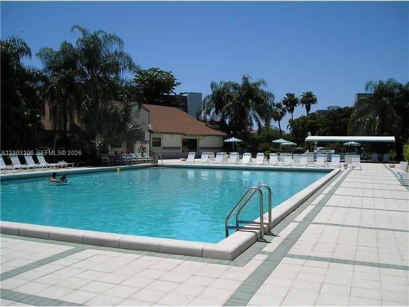 2230 N Cypress Bend Drive, #308, Pompano Beach, Pompano Beach, FL 33069 Rectangular swimming pool featuring a concrete deck, metal handrails, and a surrounding paved patio area