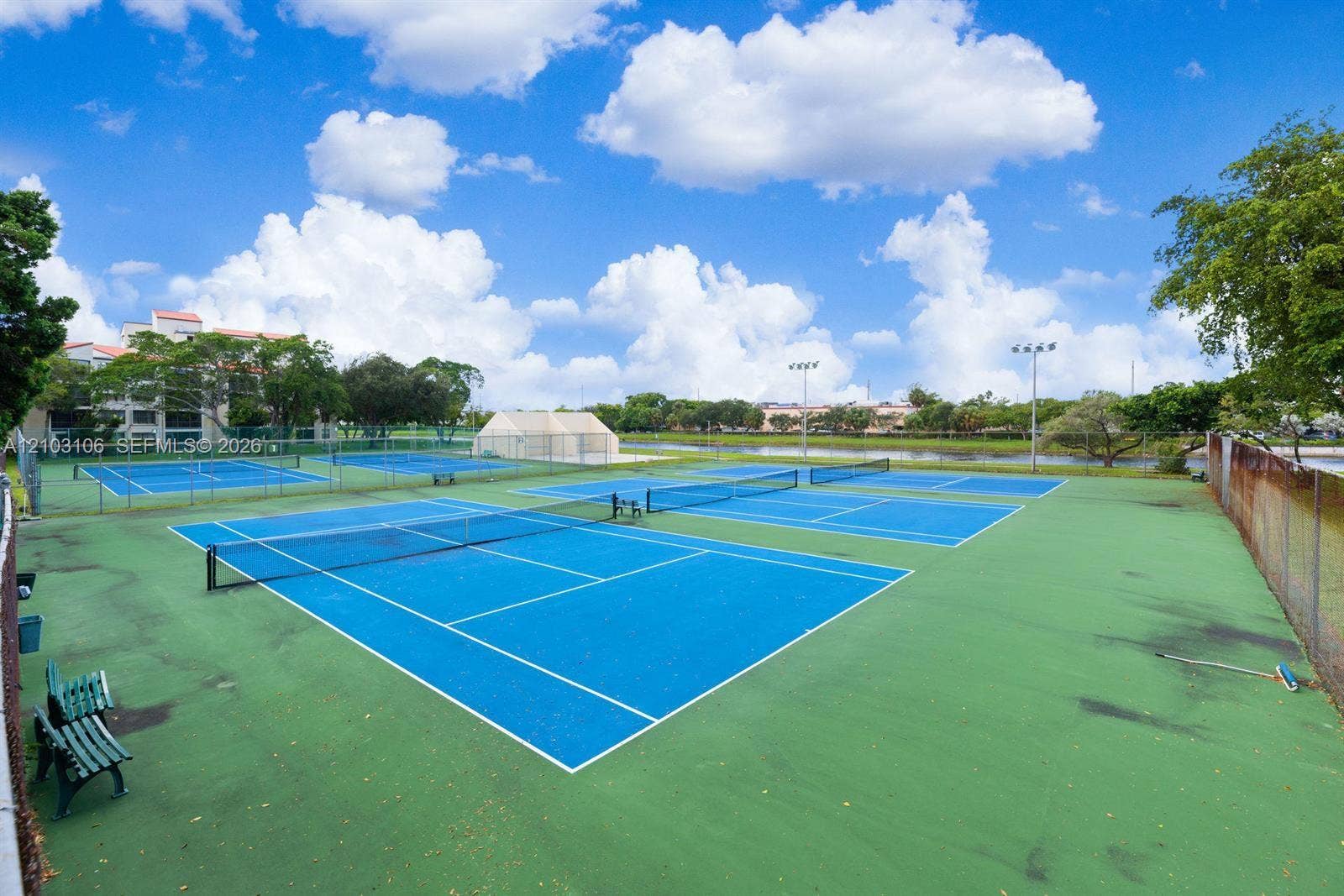 2230 N Cypress Bend Drive, #308, Pompano Beach, Pompano Beach, FL 33069 Multi-court tennis facility featuring high-visibility blue surfaces, perimeter fencing, and overhead lighting