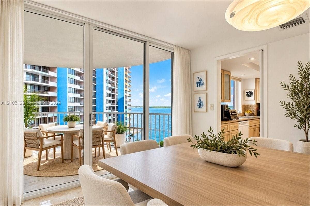 1627 Brickell Avenue, #2005, Miami, FL 33129 Floor-to-ceiling sliding glass doors, private balcony with metal railing, water frontage, and light-toned tile flooring