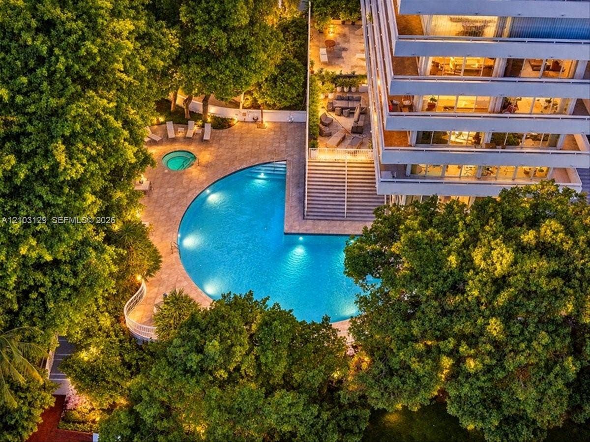 1627 Brickell Avenue, #2005, Miami, FL 33129 Multi-level building exterior featuring a crescent-shaped swimming pool, built-in spa, stone-finish pool deck, and mature landscaping
