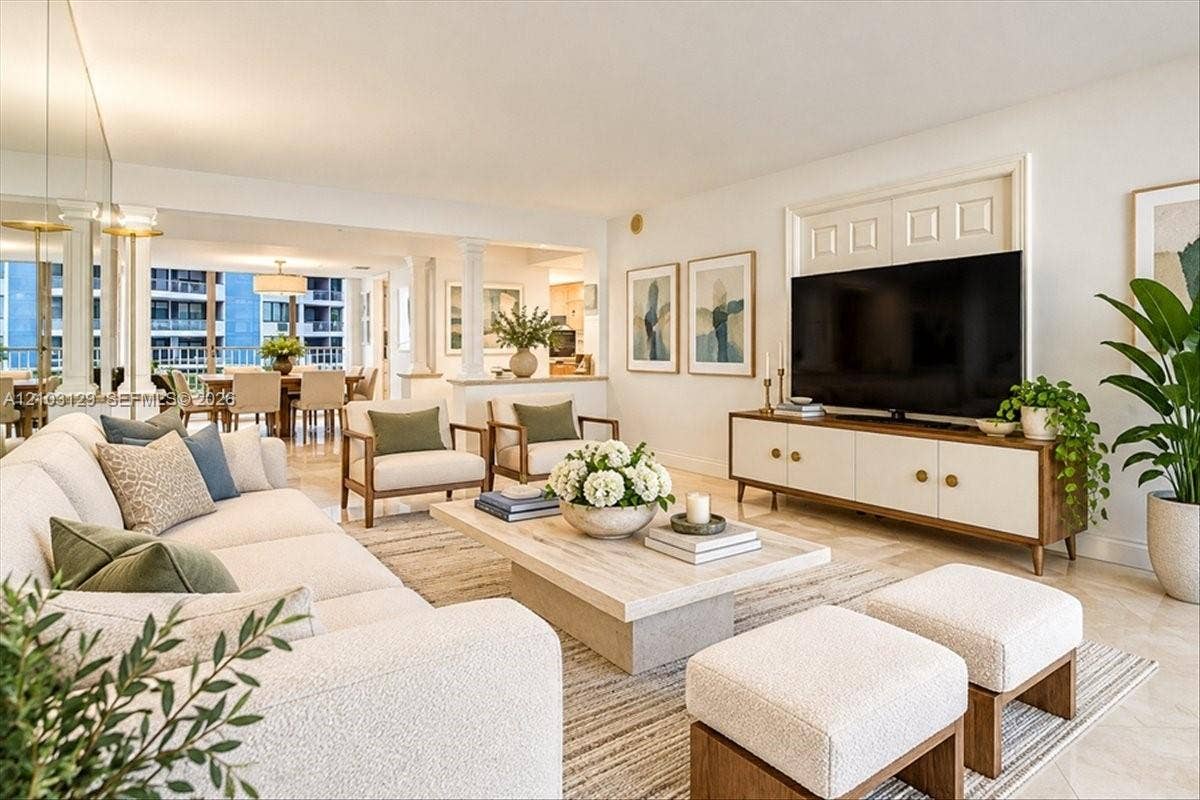 1627 Brickell Avenue, #2005, Miami, FL 33129 Open-concept interior featuring light-toned stone tile flooring, structural columns, and mirrored wall accents